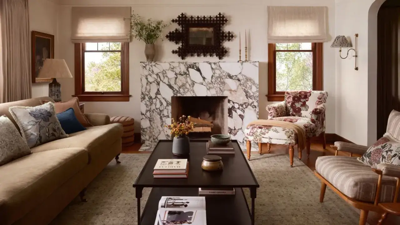 Un salon cosy avec un canap&eacute; beige, une chemin&eacute;e en marbre, et une belle id&eacute;e d&eacute;co coin salon avec des fauteuils fleuris.