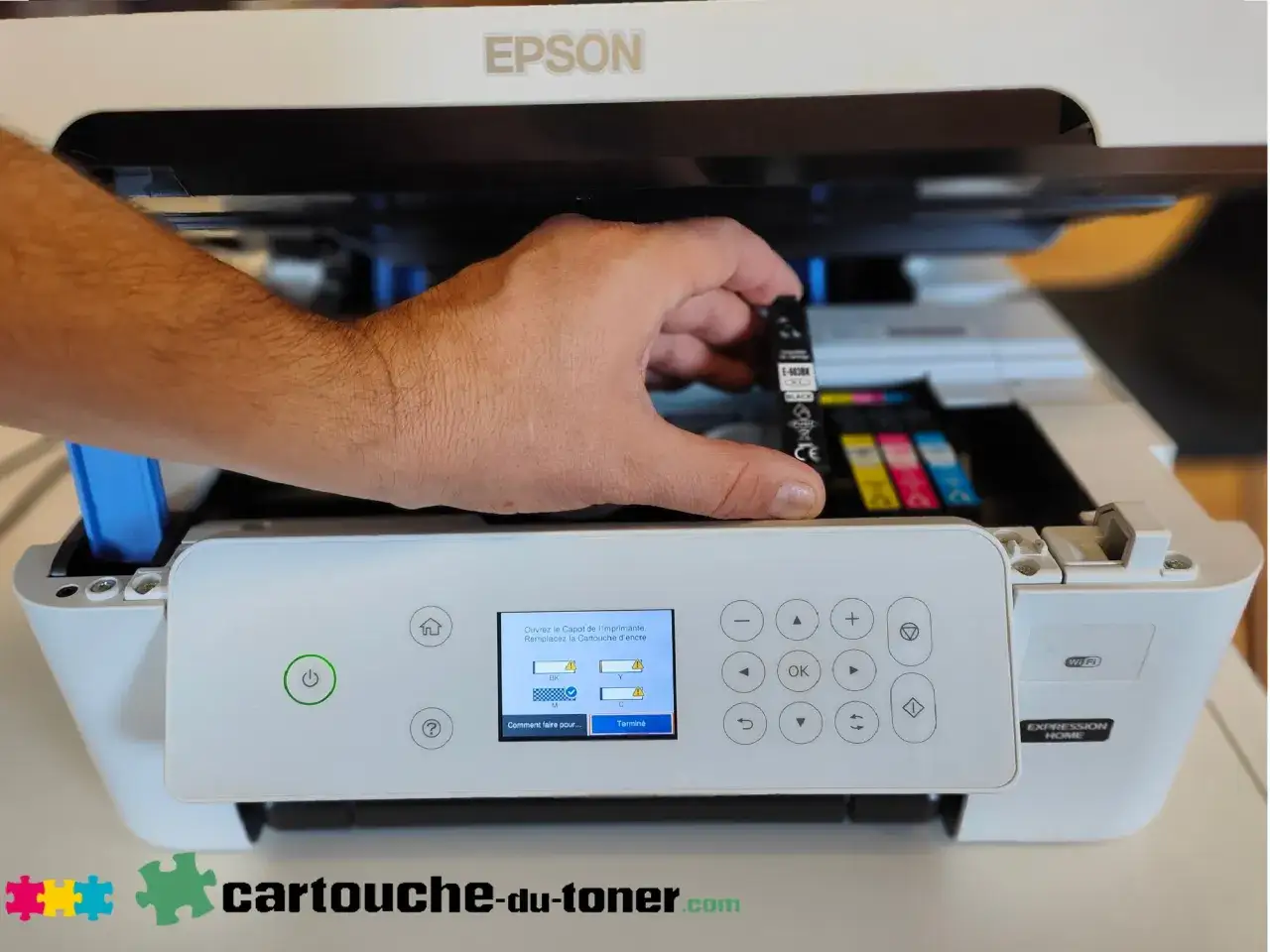 Main tenant une cartouche d'encre noire pour la changer dans une imprimante Epson. L'écran indique