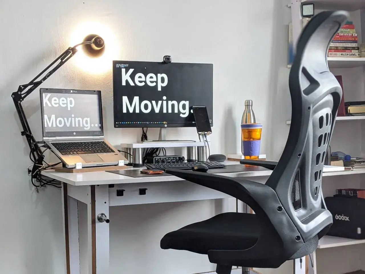 Bureau avec ordinateur portable, écran, lampe et chaise. Le message
