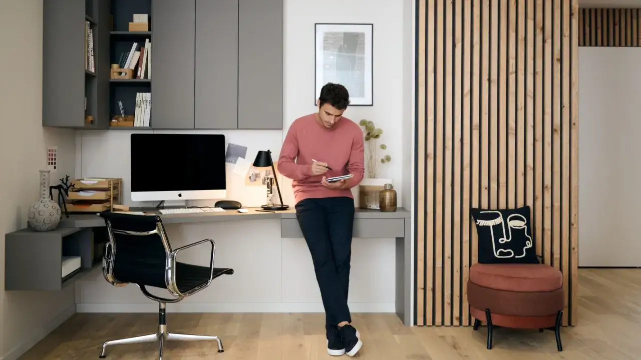 Un homme travaille dans un bureau moderne, créant une ambiance de dimension bureau chambre.