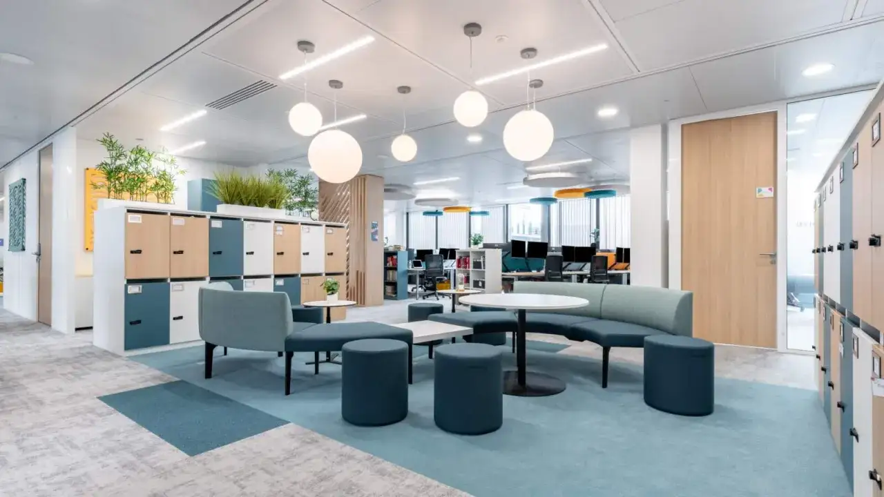 Espace ouvert et lumineux, idéal pour un bureau flexible. Canapés modulables, casiers colorés et plantes vertes créent une ambiance conviviale.