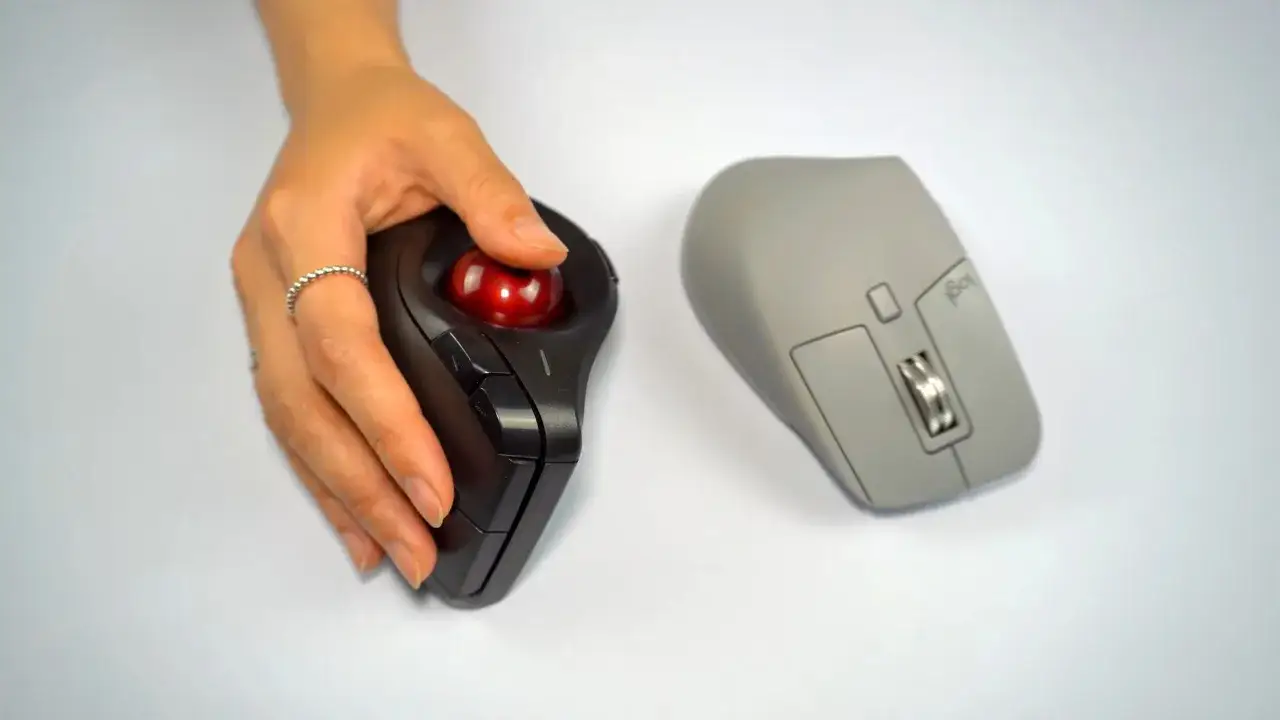 Main gauche, une main utilise une souris trackball noire. &Agrave; droite, une souris grise. Quelle souris ergonomique choisir pour votre confort ?