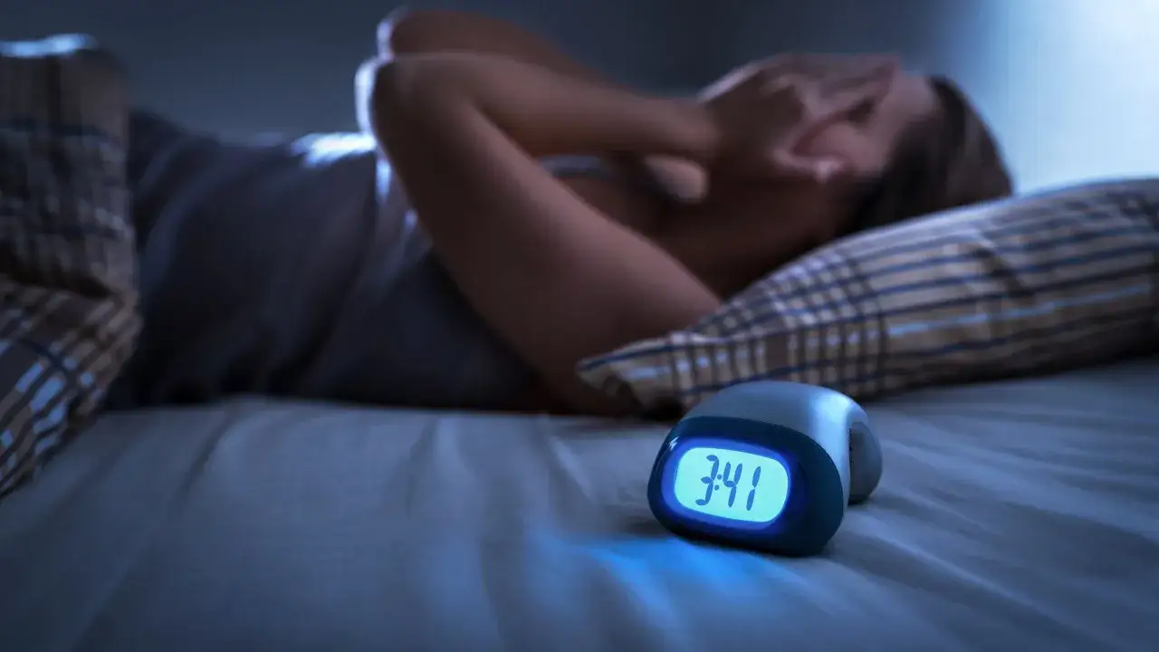 Une personne souffre d'insomnie, le stress du travail l'emp&ecirc;che de dormir. L'horloge affiche 3h41.