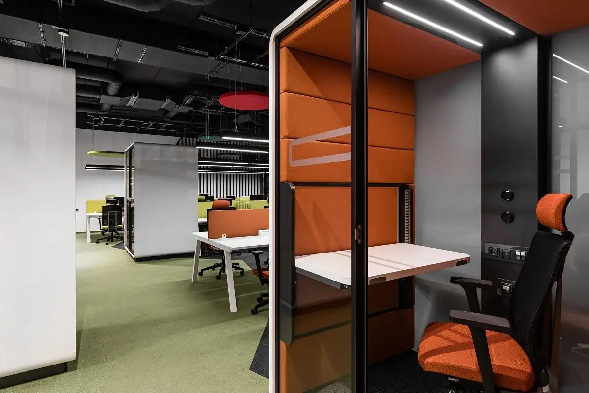 Cabine individuelle orange et grise pour l'isolation acoustique de bureau. Si&egrave;ge ergonomique, table rabattable et &eacute;clairage int&eacute;gr&eacute;.