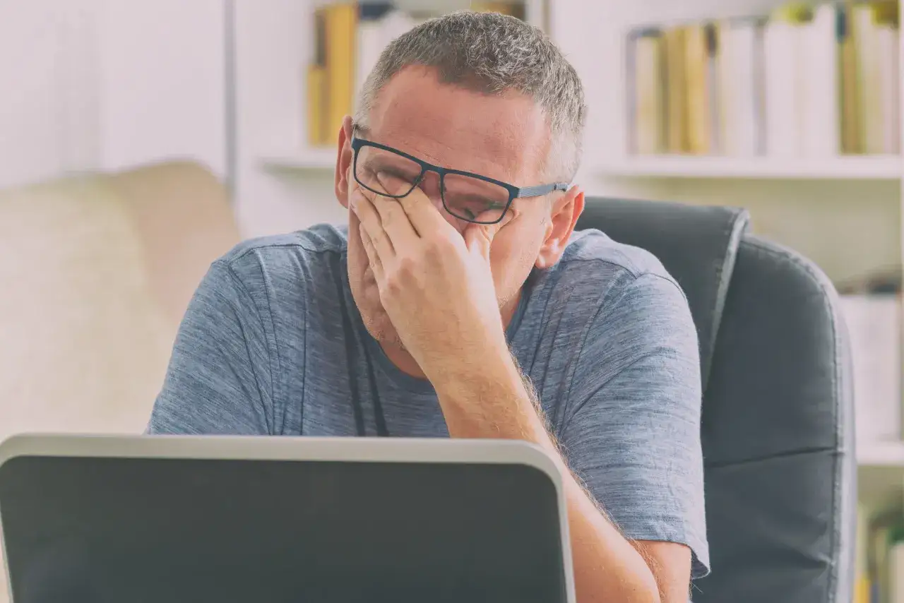 Homme fatigu&eacute; devant son ordinateur, se frottant les yeux. Il cherche des solutions pour comment r&eacute;duire la fatigue.