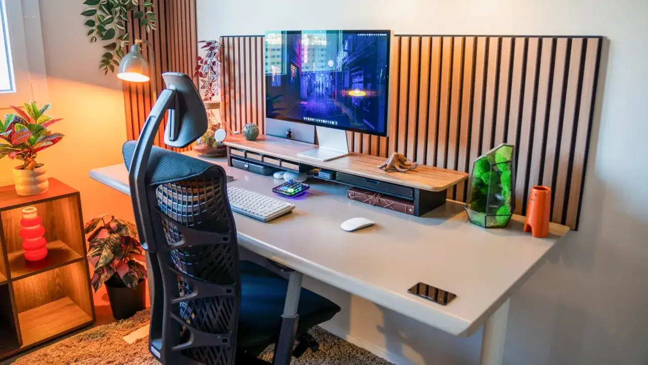 Bureau moderne pour un poste en télétravail, avec écran, clavier, souris, plantes et décoration.
