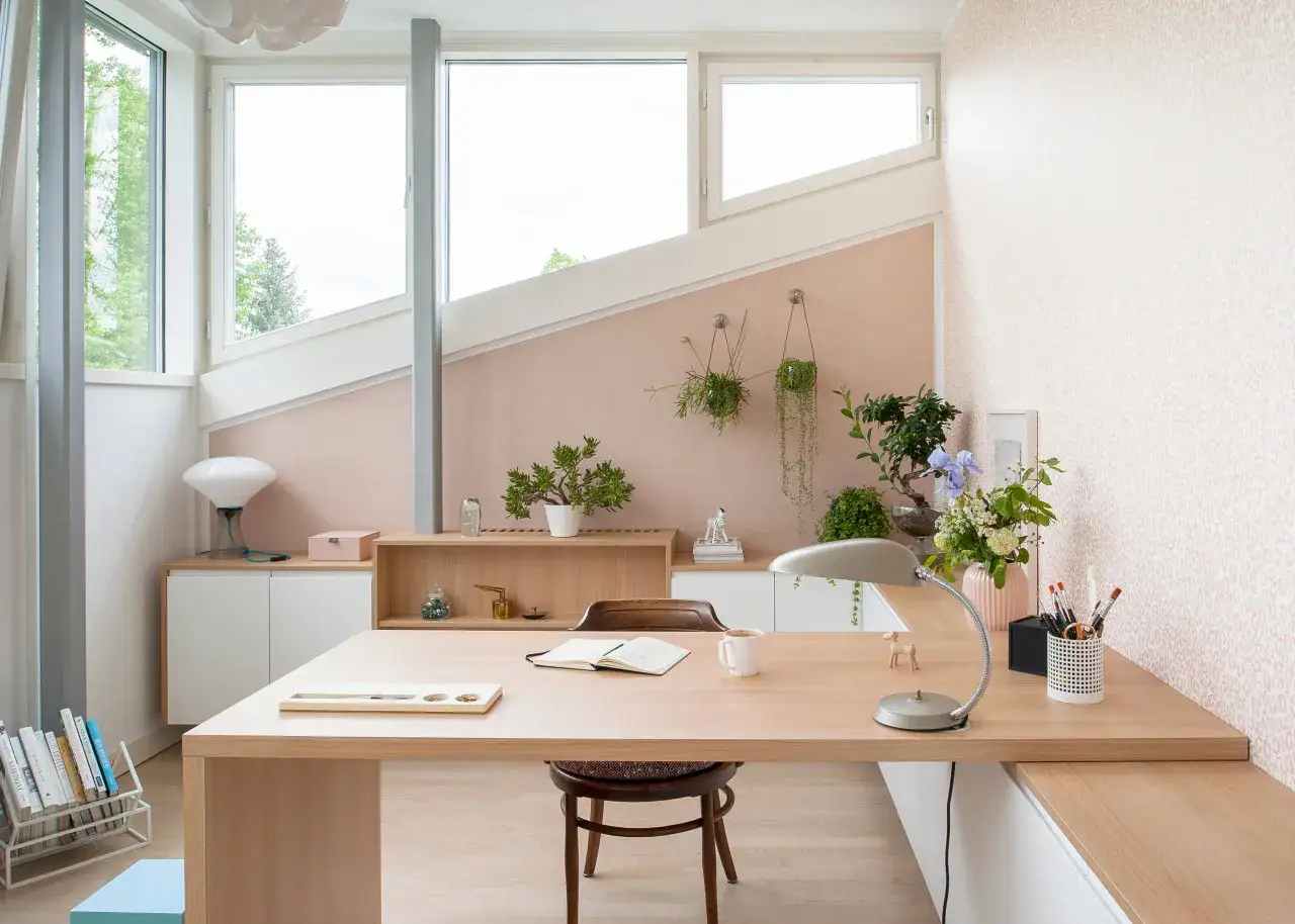 Un bureau zen au travail, avec des plantes suspendues, une lampe design et une vue sur la nature. Un espace calme et inspirant.