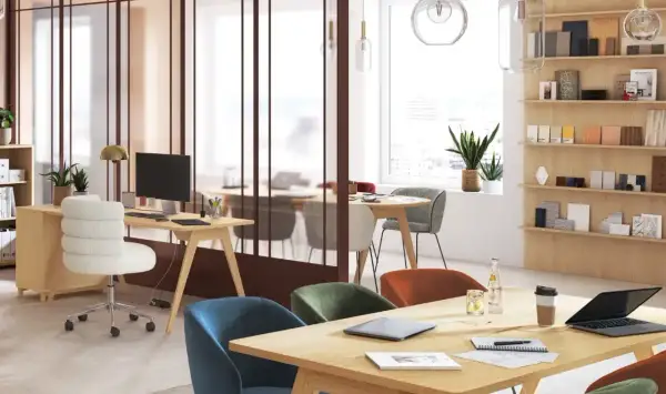 Aménagement espace coworking lumineux avec bureaux en bois, chaises colorées et étagères remplies d'échantillons.
