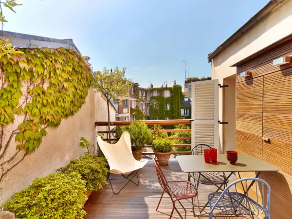 Une belle idee amenagement terrasse : mobilier coloré, plantes luxuriantes et vue sur les toits. Parfait pour un moment de détente.