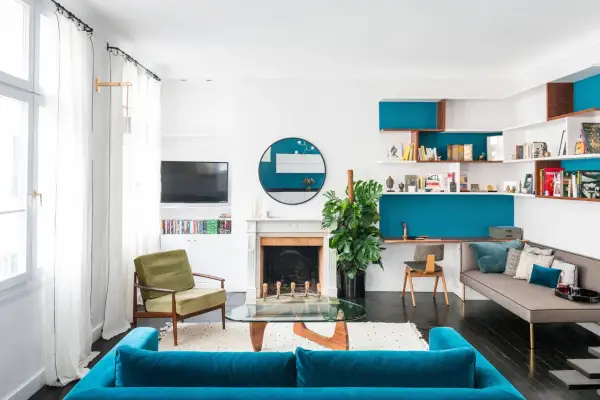 Un coin salon moderne avec canapé bleu, fauteuil vert, étagères murales turquoise et bureau intégré. Idées pour que mettre dans un coin de salon.