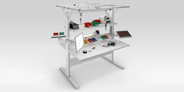 Poste aménagé avec écran, bacs de rangement colorés, outils et composants pour un travail organisé.
